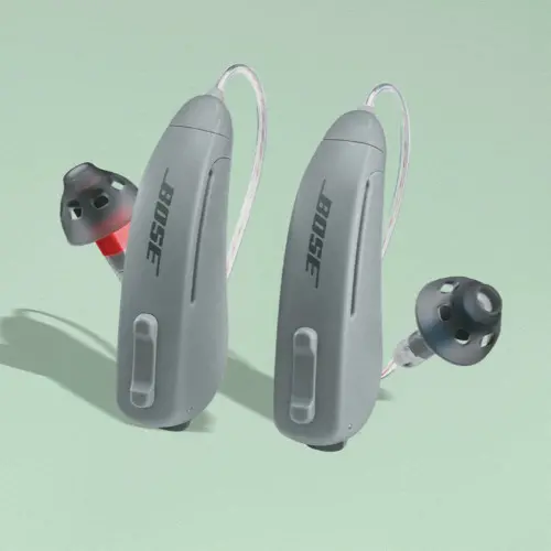 Gray behind-the-ear Lexie hearing aids on a green background with shadow