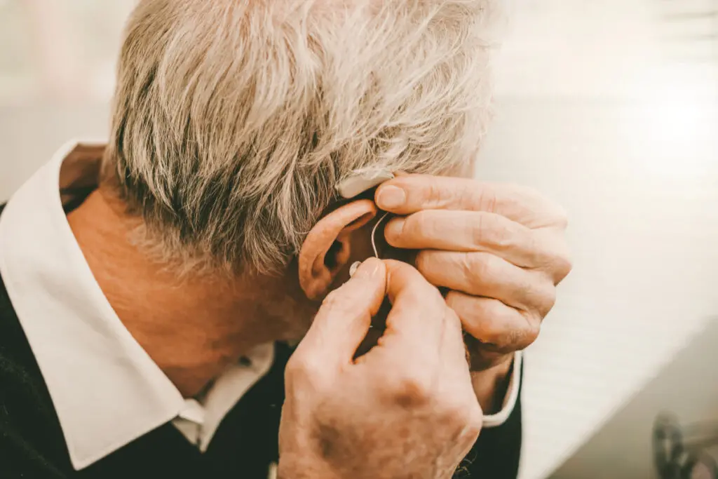 Man putting on hearing aid