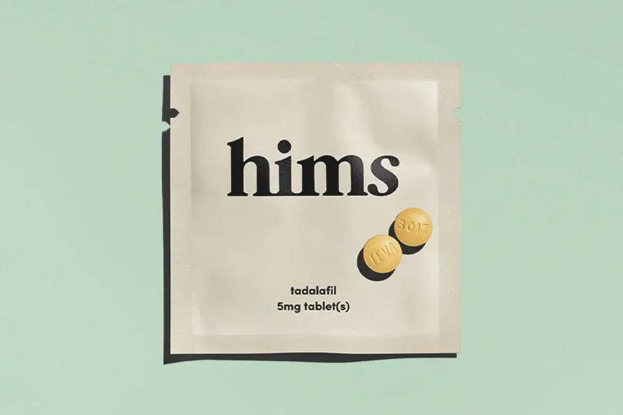 Two yellow pills on a Hims sachet against a green background