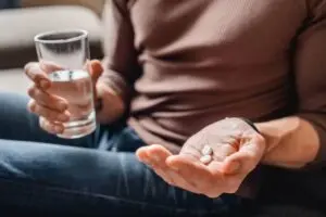 Hands holding glass of water and pills